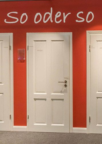 Weiße Innentüren vor roter Wand mit der Aufschrift „So oder so“